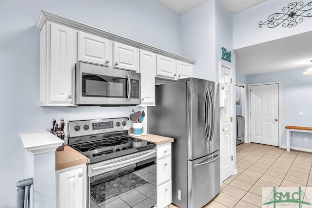 kitchen with light tile patterned flooring, white cabinets, and appliances with stainless steel finishes