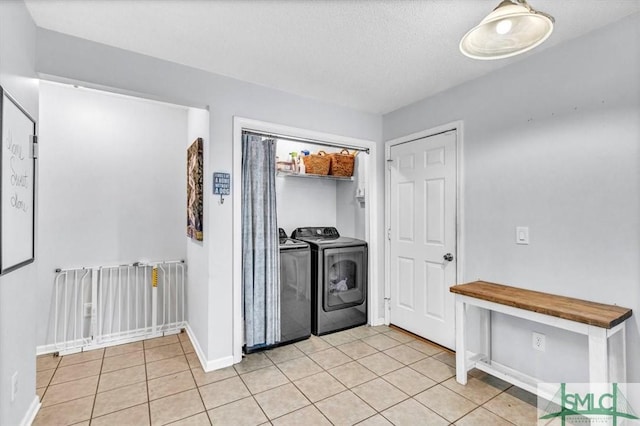 washroom featuring light tile patterned floors, washing machine and dryer, and a textured ceiling