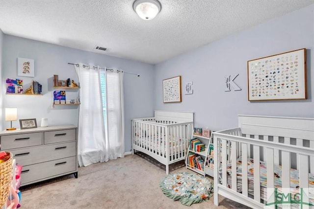 bedroom with a nursery area, light colored carpet, and a textured ceiling