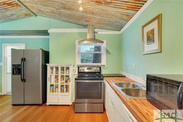 kitchen with lofted ceiling, sink, wooden counters, appliances with stainless steel finishes, and white cabinets