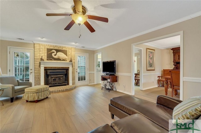 living room with light hardwood / wood-style flooring, ornamental molding, and plenty of natural light