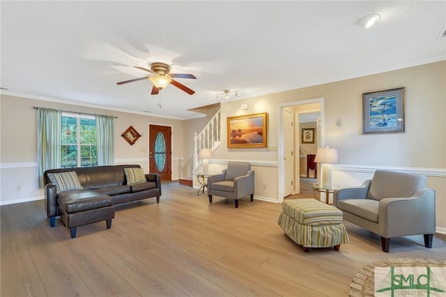 living room featuring ornamental molding, ceiling fan, and light wood-type flooring