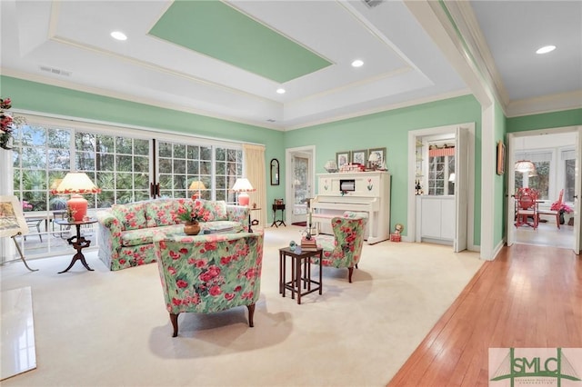 carpeted living room with crown molding and a tray ceiling