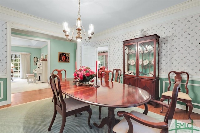 dining room featuring ornamental molding, hardwood / wood-style floors, and a notable chandelier