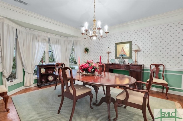 dining space with hardwood / wood-style flooring, ornamental molding, and a chandelier