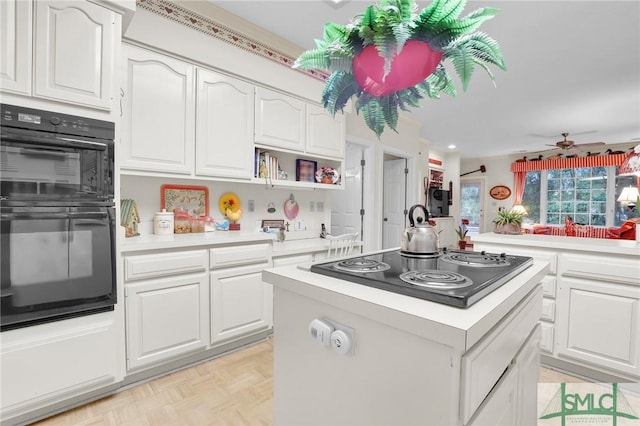 kitchen featuring white cabinets, a center island, light parquet floors, and black appliances