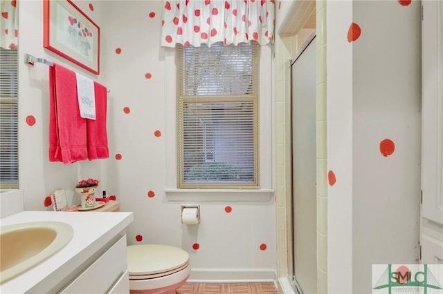 bathroom featuring a shower with door, vanity, and toilet