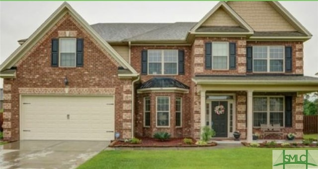 view of front of property featuring a garage, covered porch, and a front lawn