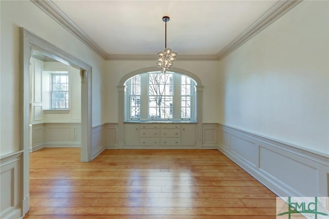 unfurnished room featuring crown molding, light hardwood / wood-style flooring, and a notable chandelier