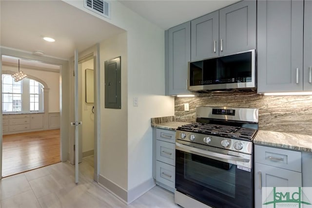 kitchen featuring appliances with stainless steel finishes, backsplash, electric panel, light stone countertops, and light tile patterned flooring