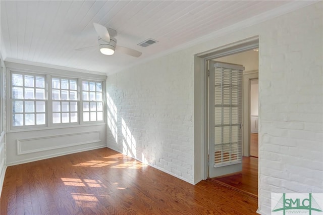 unfurnished room featuring crown molding, wood-type flooring, wooden ceiling, ceiling fan, and brick wall