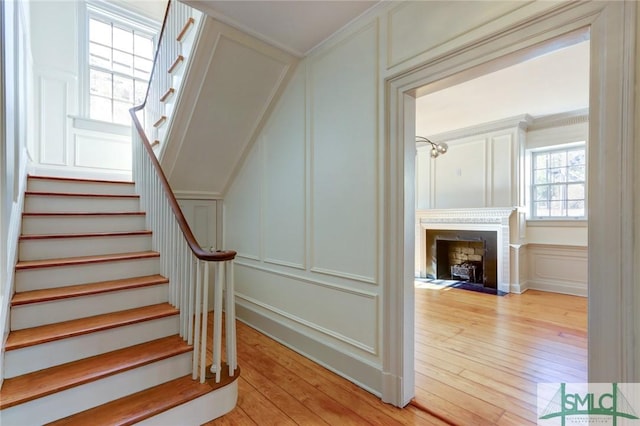 stairs with hardwood / wood-style flooring and ornamental molding