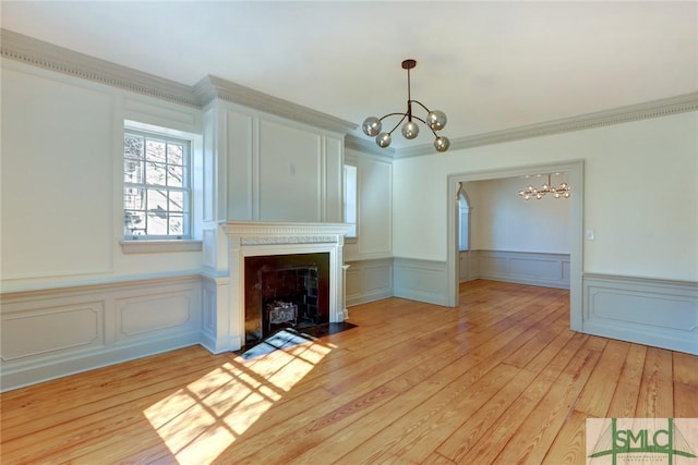 unfurnished living room featuring ornamental molding, light hardwood / wood-style floors, and a chandelier