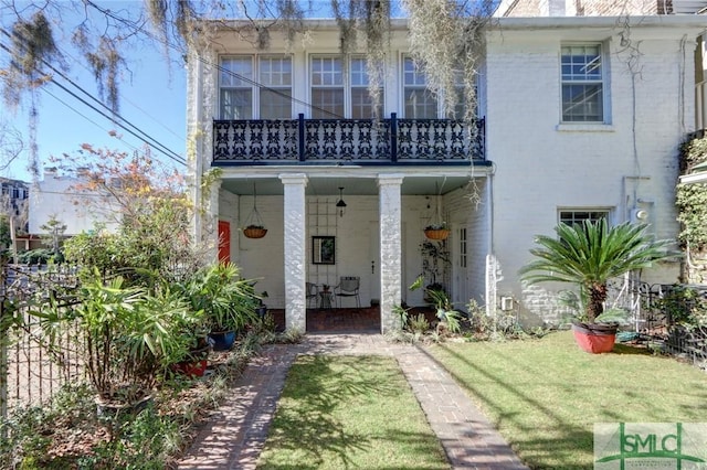 rear view of property featuring a lawn and a balcony