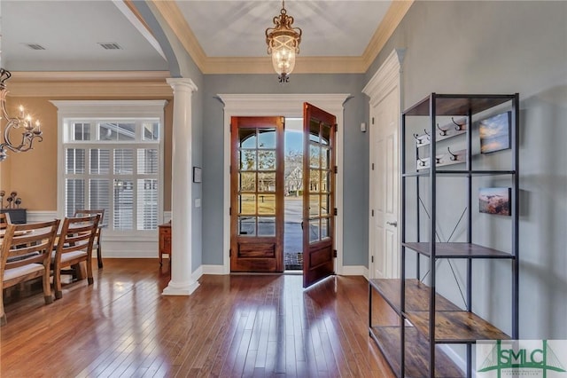 entrance foyer with an inviting chandelier, ornamental molding, and ornate columns