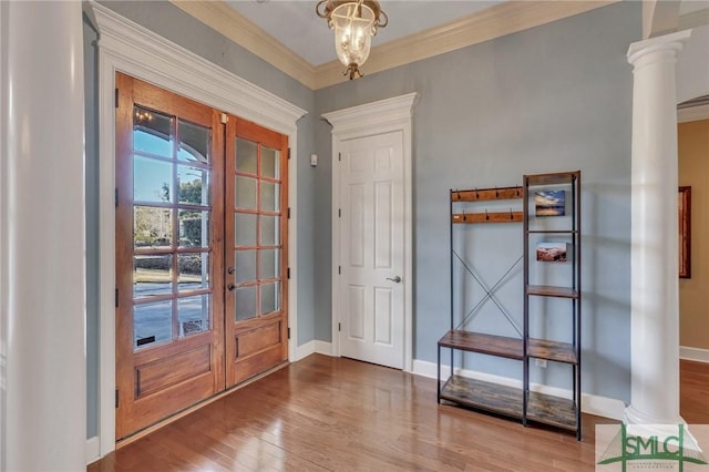 entryway featuring french doors, ornate columns, a chandelier, ornamental molding, and hardwood / wood-style floors