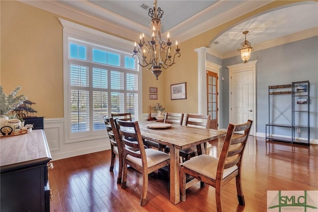 dining room featuring dark wood-type flooring, ornamental molding, and ornate columns