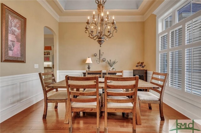 dining space featuring a raised ceiling, crown molding, hardwood / wood-style floors, and an inviting chandelier