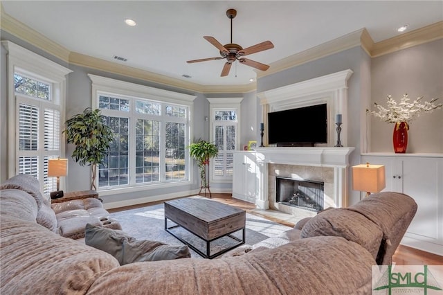 living room featuring a fireplace, ornamental molding, light hardwood / wood-style floors, and ceiling fan