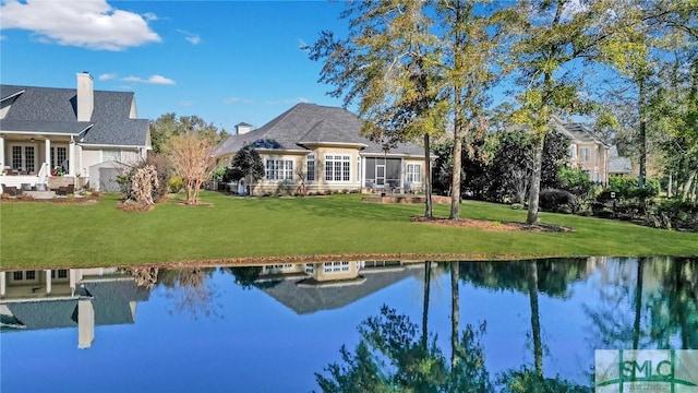 exterior space with a lawn, a sunroom, and a water view