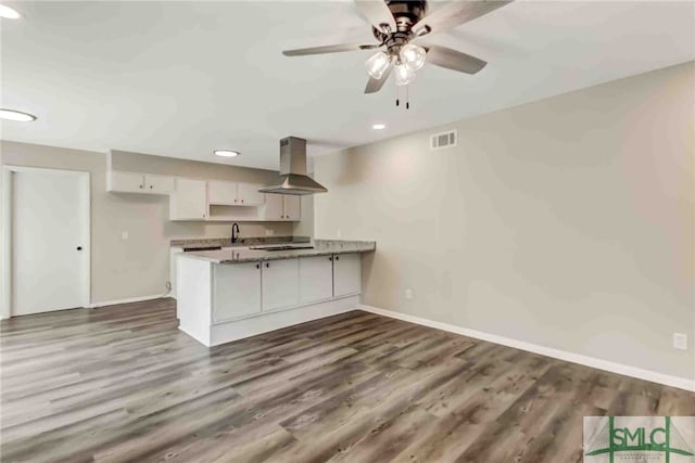 kitchen with island range hood, wood-type flooring, white cabinets, ceiling fan, and kitchen peninsula