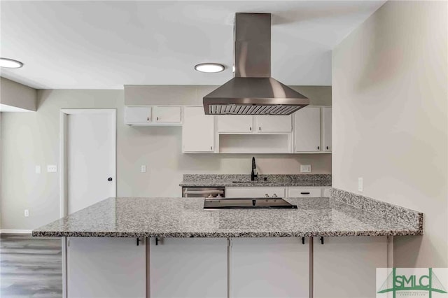 kitchen featuring sink, white cabinetry, light stone counters, kitchen peninsula, and island exhaust hood