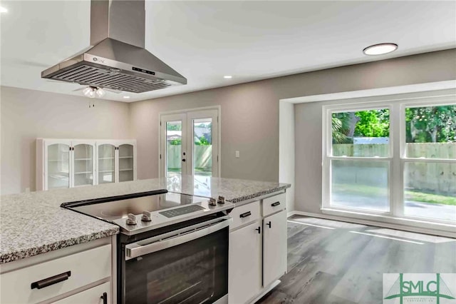 kitchen with white cabinetry, light stone counters, electric range, and island exhaust hood