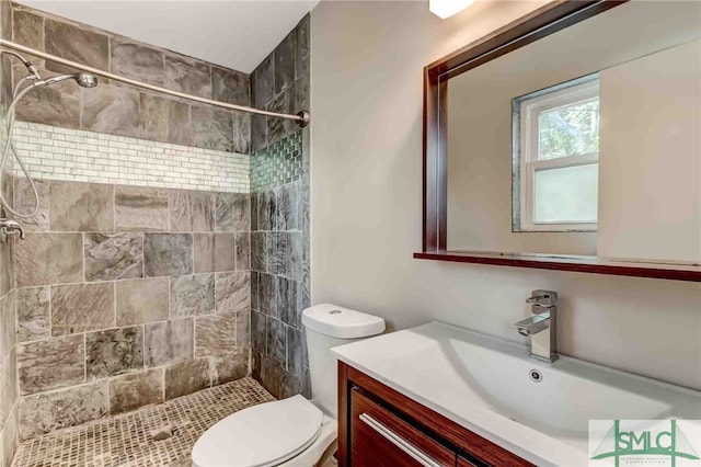 bathroom with vanity, toilet, and tiled shower