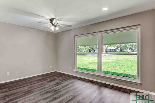 empty room featuring dark wood-type flooring, ceiling fan, and a healthy amount of sunlight