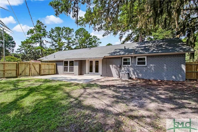 rear view of property featuring french doors, central AC unit, a patio, and a lawn