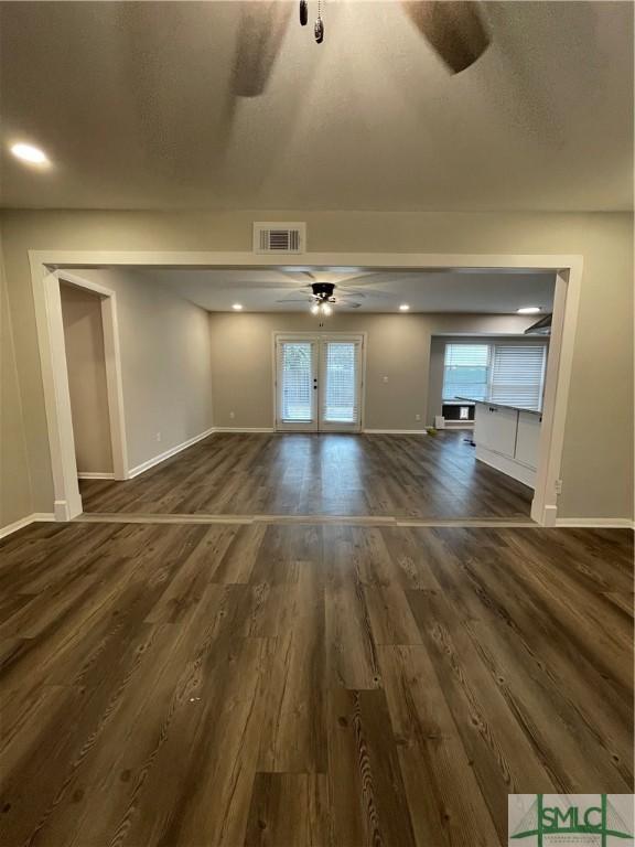 unfurnished living room featuring dark wood-type flooring, a textured ceiling, and ceiling fan