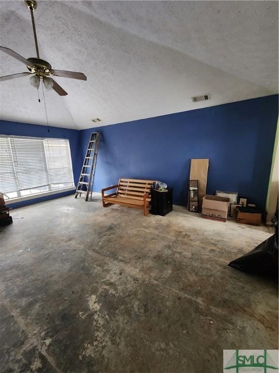 interior space featuring lofted ceiling, a textured ceiling, and concrete floors