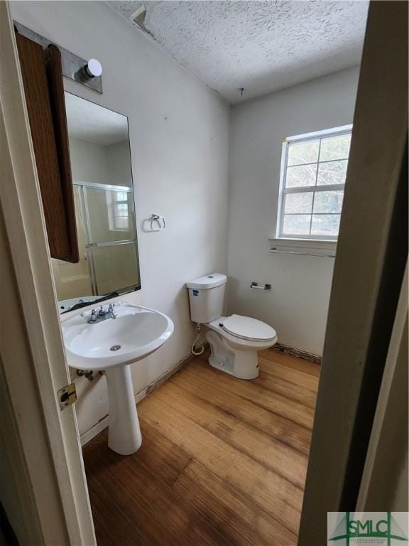 bathroom featuring hardwood / wood-style floors, a textured ceiling, and toilet