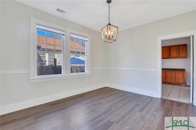 unfurnished dining area featuring hardwood / wood-style floors, a notable chandelier, and a baseboard radiator