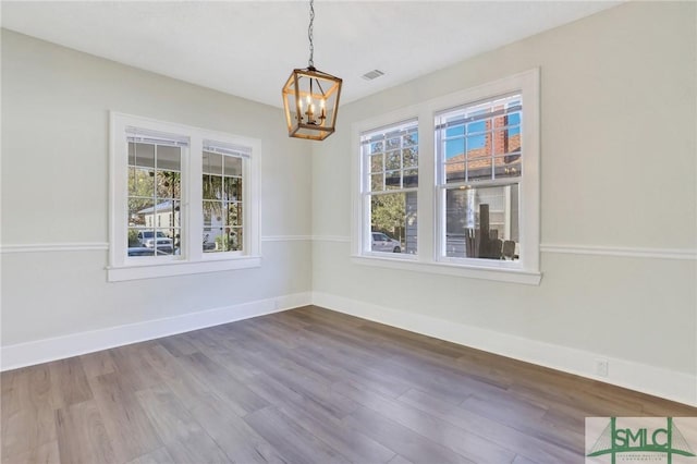 unfurnished dining area with hardwood / wood-style floors and a notable chandelier