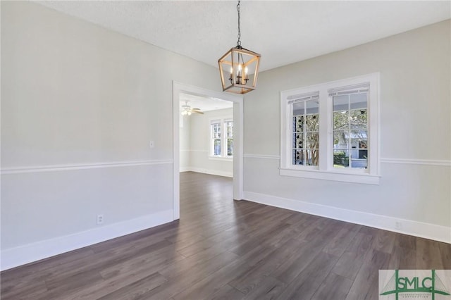 unfurnished dining area featuring ceiling fan with notable chandelier and dark wood-type flooring