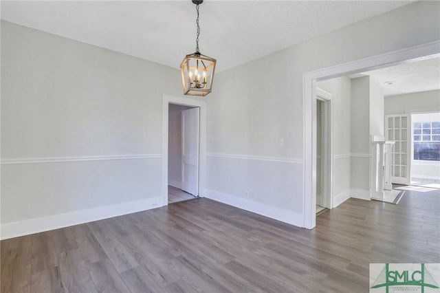 empty room featuring hardwood / wood-style floors and a notable chandelier