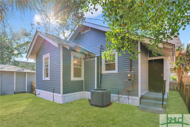 back of property featuring cooling unit and a yard