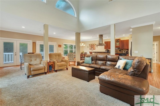 living room with crown molding, a towering ceiling, light carpet, and an inviting chandelier