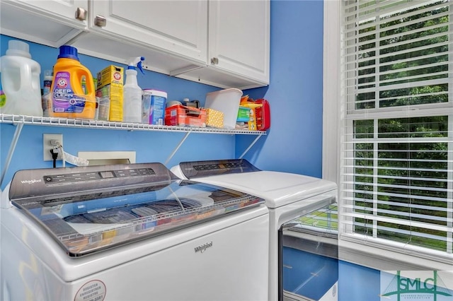 laundry room featuring cabinets, a healthy amount of sunlight, and washer and clothes dryer