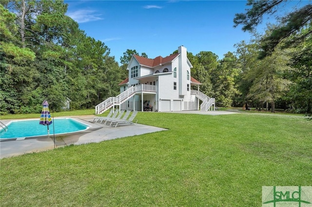 rear view of house featuring a garage, a patio area, and a lawn