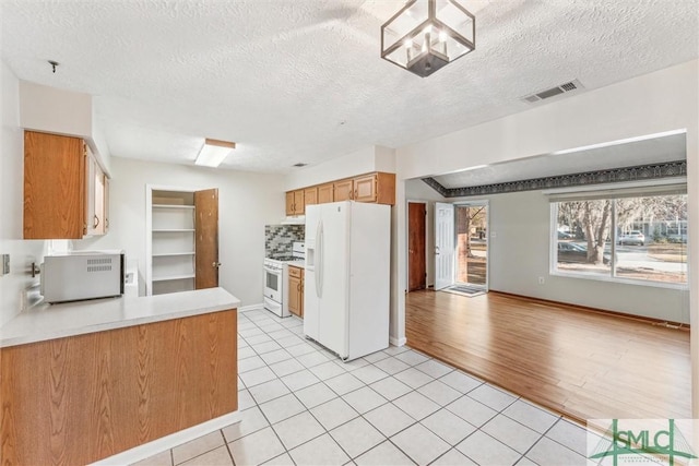 kitchen with a notable chandelier, light tile patterned floors, a textured ceiling, and white appliances