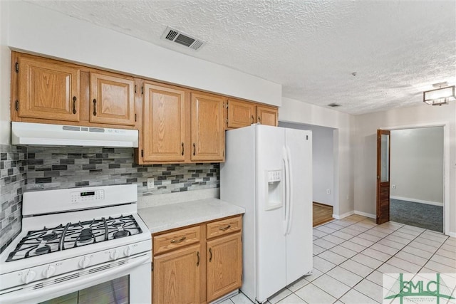 kitchen with light tile patterned floors, a textured ceiling, white appliances, and decorative backsplash