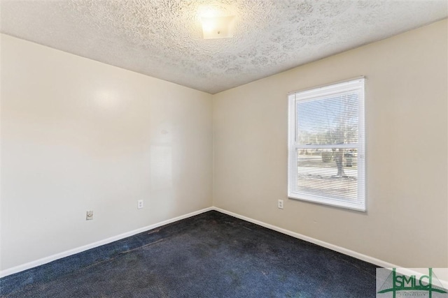 empty room with dark carpet and a textured ceiling