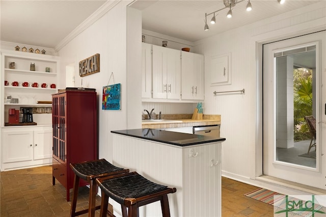 kitchen featuring white cabinetry, sink, a breakfast bar area, and ornamental molding