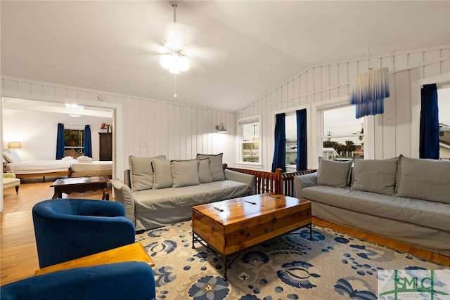 living room with lofted ceiling, hardwood / wood-style flooring, ceiling fan, and wood walls