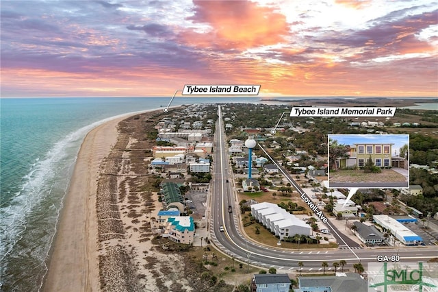 aerial view at dusk featuring a water view and a view of the beach