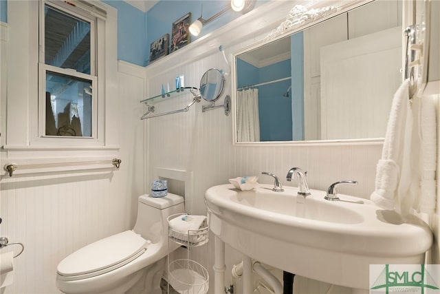 bathroom featuring crown molding, toilet, sink, and a shower with curtain