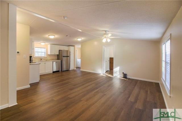 unfurnished living room with vaulted ceiling, sink, ceiling fan, and dark hardwood / wood-style flooring