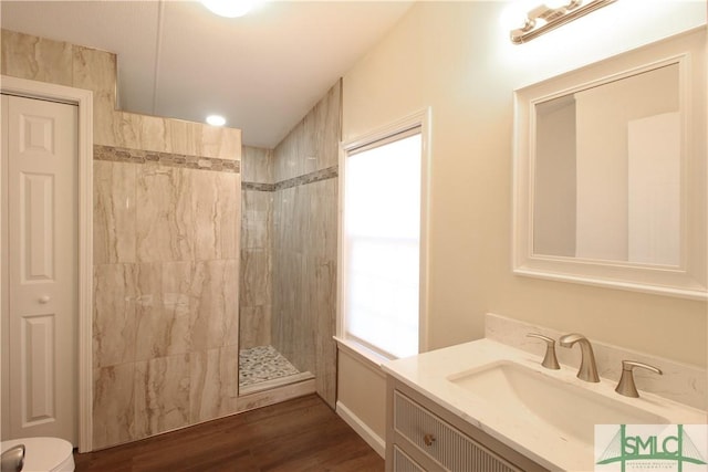 bathroom with wood-type flooring, tiled shower, and vanity